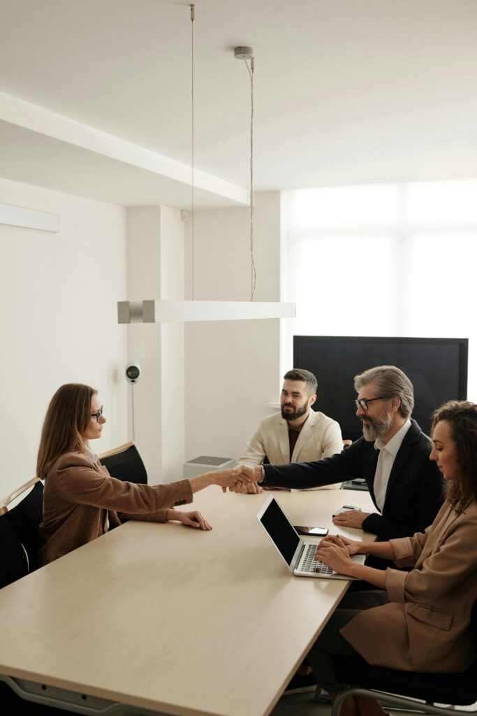 pexels photo 4342493 4342493 Business professionals engaging in a handshake across a conference table, signifying successful collaboration.